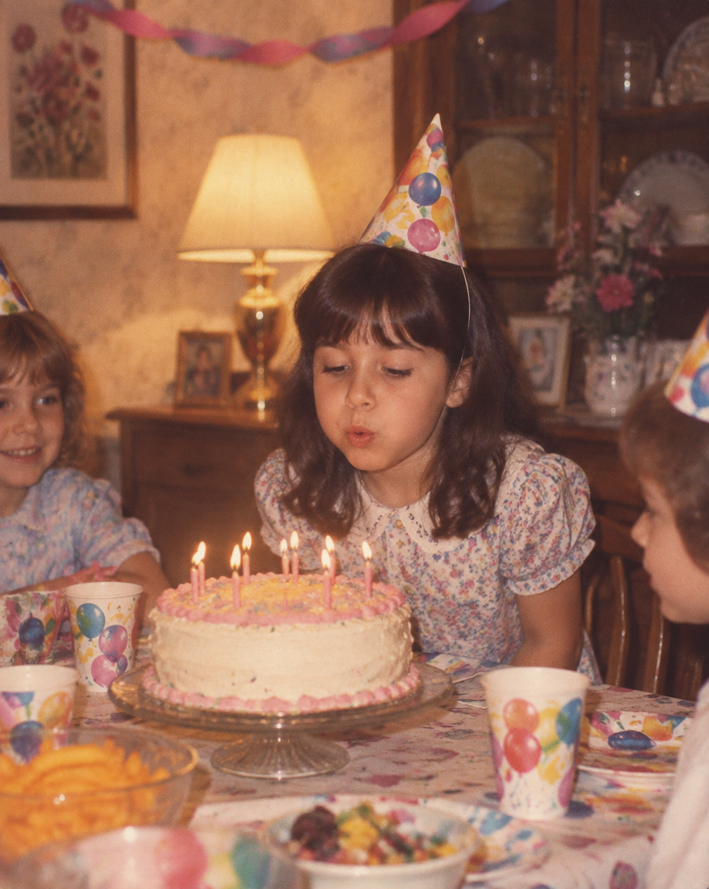 Young Melissa blowing out the candles at a birthday party her mom made for her